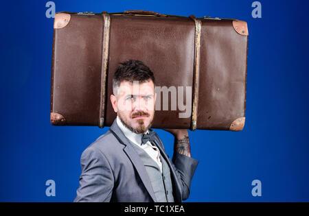 heavy bag. mature traveller. bearded man in formal suit. stylish esthete with vintage bag. businessman in bow tie. business trip with retro suitcase. Elegance and style. Trendy and handsome. Stock Photo