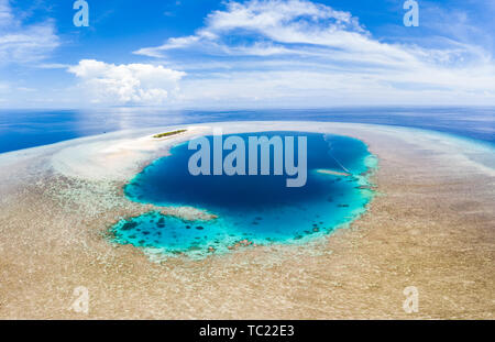 Aerial: tropical atoll view from above, blue lagoon turquoise water coral reef, Wakatobi Marine National Park, Indonesia - concept travel destination 