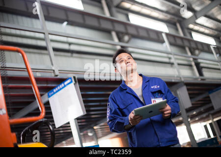 young man technician working with tablet in manufacturing factory Stock Photo