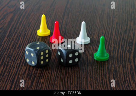 Four chips of different colors and two dice for Board games on a wooden surface. Stock Photo