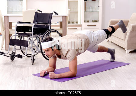 Injured young man doing exercises at home Stock Photo