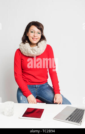 Front view of beautiful woman in casual wear sitting on a stool while looking camera against white background Stock Photo