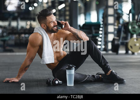 Muscular guy talking on cellphone after training at gym Stock Photo