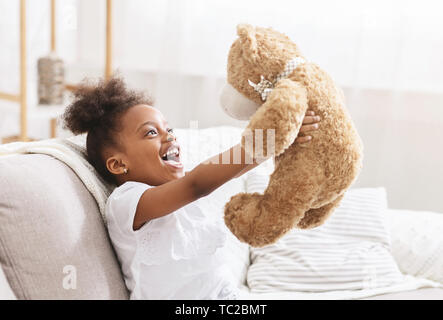 Cute african american child hugging teddy bear and smiling