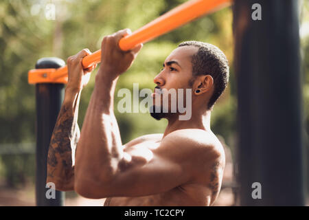 Sport And Lifestyle. Afro Man Doing Pull Ups On Horizontal Bar Stock Photo