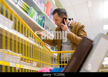 man using cell phone in grocery shop Stock Photo
