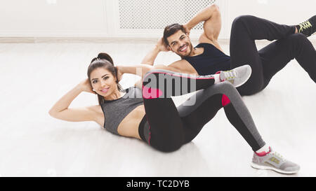 Happy couple doing sport exercises on the floor in studio Stock Photo