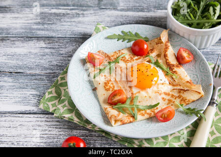 Crepes with eggs, cheese, arugula leaves and tomatoes.Galette complete. Traditional dish galette sarrasin Stock Photo