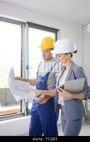 Construction worker and architect looking at plan on site Stock Photo