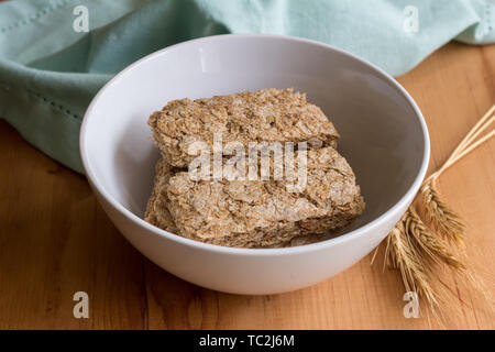 Wheat cereal in bowl with wheat spears on wooden table Stock Photo