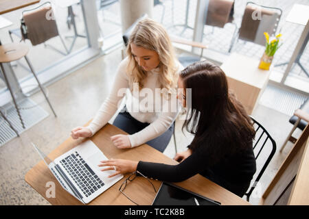 Top view of two women working on project at modern coffee shop in city Stock Photo
