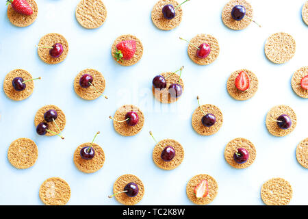 Seamless summer pattern, flat lay with repeating biscuits from cookies and strawberries and cherries. Stock Photo