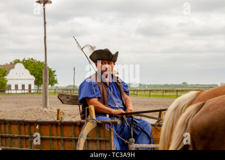 Kalocsa, Puszta, Hungary - May 23, 2019 : Portrait of traditioanl Hungarian Csikos horseman riding cart in rural corral. Stock Photo