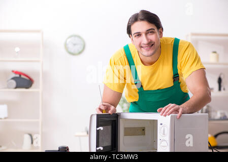 Young repairman repairing microwave in service centre Stock Photo