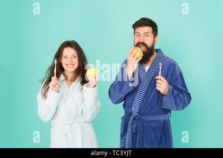 Healthy habits. Brush teeth every morning. Oral hygiene. Couple bathrobes hold toothbrushes and apples. Personal hygiene. Couple in love cleaning teeth. Freshness and cleanliness. Keep teeth healthy. Stock Photo
