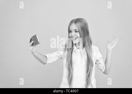 Hello world this is my channel. Let me take selfie. Child girl hold smartphone. Video call concept. Girl hold smartphone taking selfie. Selfie for social networks. Streaming online or shooting vlog. Stock Photo