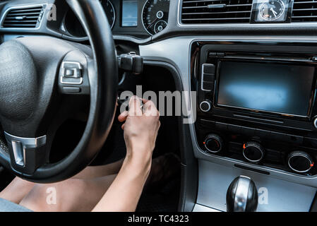 cropped view of woman putting car key in keyhole while sitting in car Stock Photo