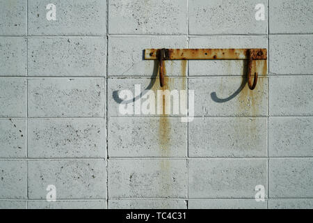 Rusty hooks on a rust stained breeze block wall at the sea front. Stock Photo