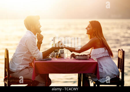 People, vacation, love and romance concept. Young couple enjoying a romantic dinner on beach. Stock Photo