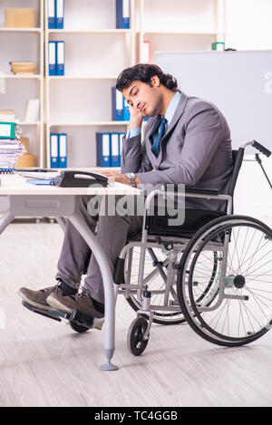 Young handsome employee in wheelchair at the office Stock Photo
