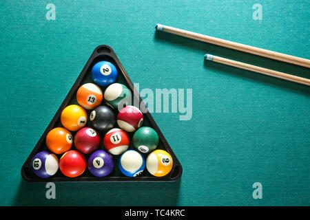 Billiard balls in triangle rack with cues on table Stock Photo