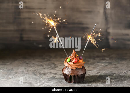 Tasty chocolate cupcake with sparklers on grunge background Stock Photo
