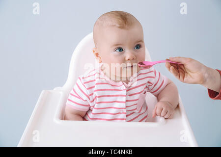 Cute little baby eating tasty food on grey background Stock Photo