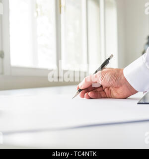 Low angle view of architect or engineer working on a project drawing with pencil. Stock Photo