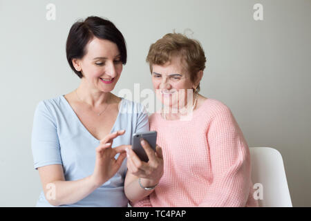 Young woman helping older female using smartphone  Stock Photo