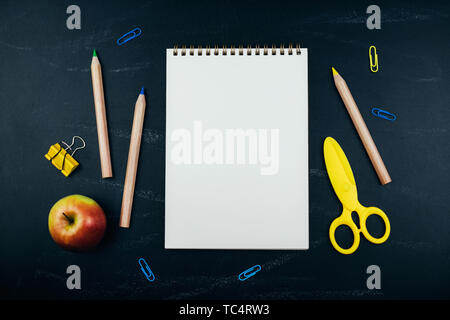 Different school supplies on black chalkboard background. Back to school background. Flat lay, copy space. Stock Photo