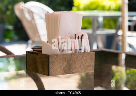 box with paper napkins on a glass table, close-up. part of the table setting outdoor summer cafe Stock Photo