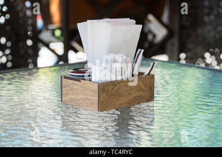 box with paper napkins on a glass table, close-up. part of the table setting outdoor summer cafe Stock Photo