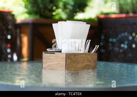 box with paper napkins on a glass table, close-up. part of the table setting outdoor summer cafe Stock Photo