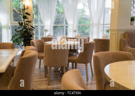 modern restaurant interior with windows and flowers. cafe room illuminated by sunlight Stock Photo