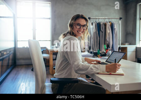 Happy woman business owner writing notes in diary. Online store working at her desk. Stock Photo