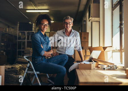 Portrait of man and woman standing in online store warehouse. Business partners together looking at camera and smiling.