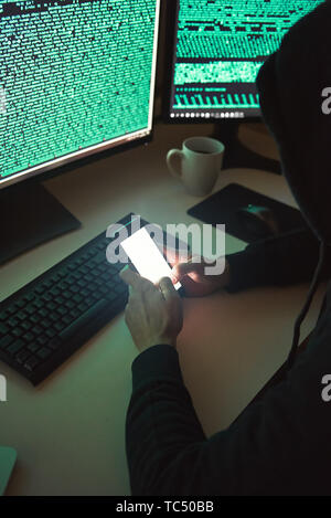 hacker with smartphone and computers in dark room Stock Photo - Alamy