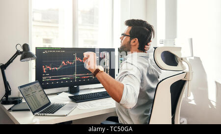 Overworked. Back view of tired young beard businessman or trader in formal weartouching his head and stretching while sitting in office. Stock broker. Forex market. Trade concept Stock Photo