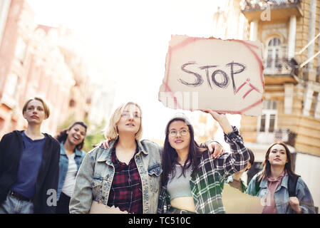 Stop violence against women. Two young women are holding a banner with word stop it while standing on the road during a women's march in front of female activists. Women rights. Human rights Stock Photo