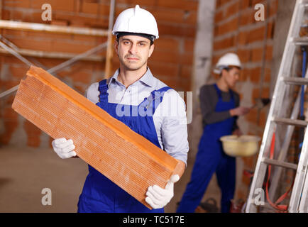 Portrait of two confident workers in uniform inside brick cottage Stock Photo