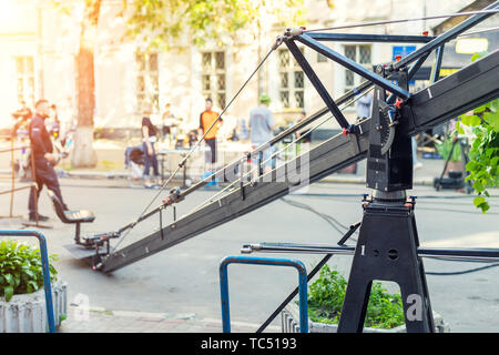 Movie set with professional equipment and media production team on city street. Outdoor film making. Big camera crane with cameraman seat at open air Stock Photo