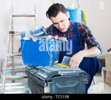 serious builder handyman choosing necessary tool in toolbox Stock Photo