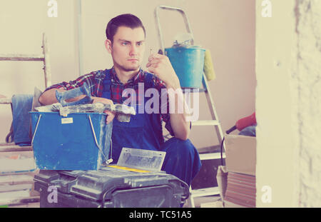 Serious worker repairing room and looking for necessary tool in toolbox Stock Photo