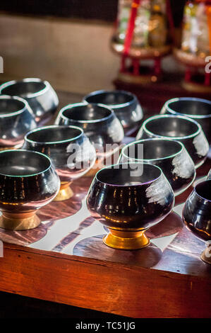 Sun light shines through the window of the temple onto bowls laid out to collect donations from worshippers. Wat Phant Tao Temple Chiang Mai. Thailand.