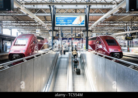 Passengers pulling their suitcases on a moving sidewalk to board on two Thalys high-speed trains in Brussels-South railway station in Belgium. Stock Photo