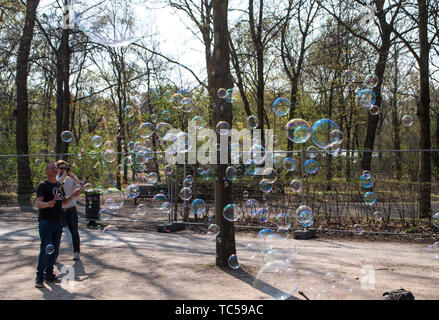 Berlin, Germany - April 6, 2019: The man who lets a lot of big soap bubbles in the park, on the street in Berlin, not far from Reichtag. It attracts m Stock Photo