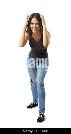 Front view of beautiful woman in gray top and blue jeans standing and leaning forward, with hands on head, smiling and wrinkling nose on white Stock Photo