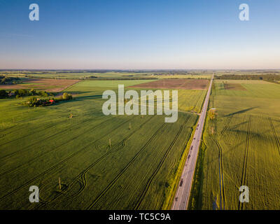 Aerial view of empty road during sunrise surrounded by agricultural fields Stock Photo