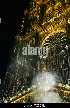 Iconic candle on top of the Christmas Chalet market stall in central Place de la Cathedrale with Notre-Dame cathedral in the background Stock Photo