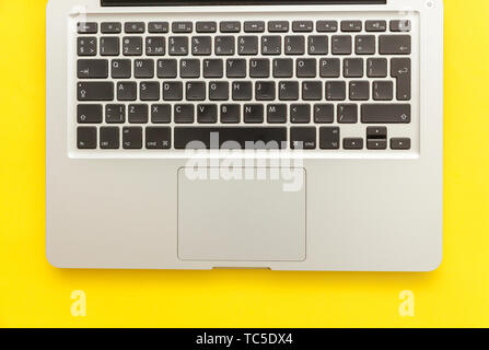 Keyboard laptop computer isolated on yellow desk background. Modern Information technology and sofware advances. Freelance home office programmer or d Stock Photo